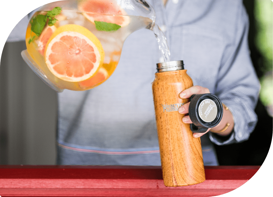 Filling Healthy Human Bottle with Water and Adding Orange Slices - Hydration with a Refreshing Twist