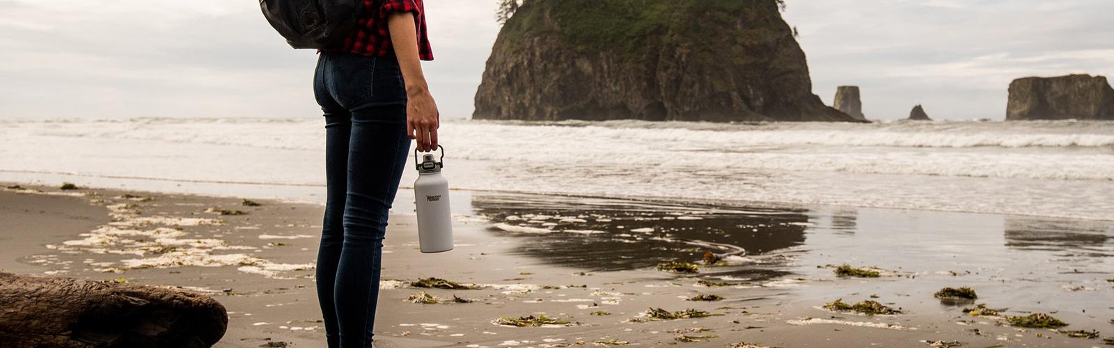 Woman Holding Healthy Human Bottle by the Seaside - Refreshing Hydration with Ocean Vibes