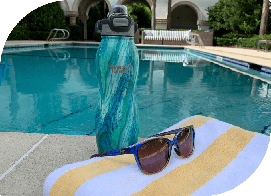 Healthy Human Bottle by the Pool with Sunglasses on the Table - Refreshing Poolside Hydration