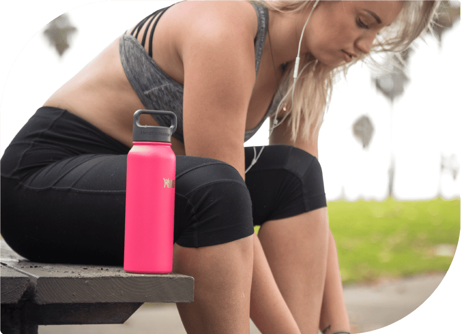 Woman Tying Shoe Laces on a Bench with Healthy Human Bottle on her Left Side - Active Lifestyle Moment
