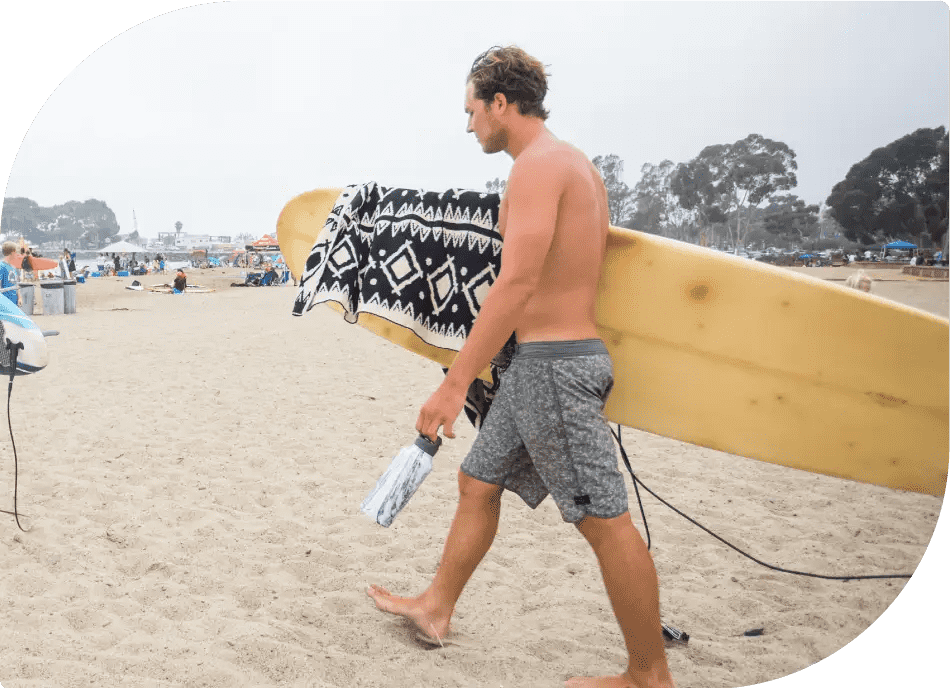 Man Holding Healthy Human Bottle on the Sandy Beach - Enjoying Refreshing Hydration by the Sea